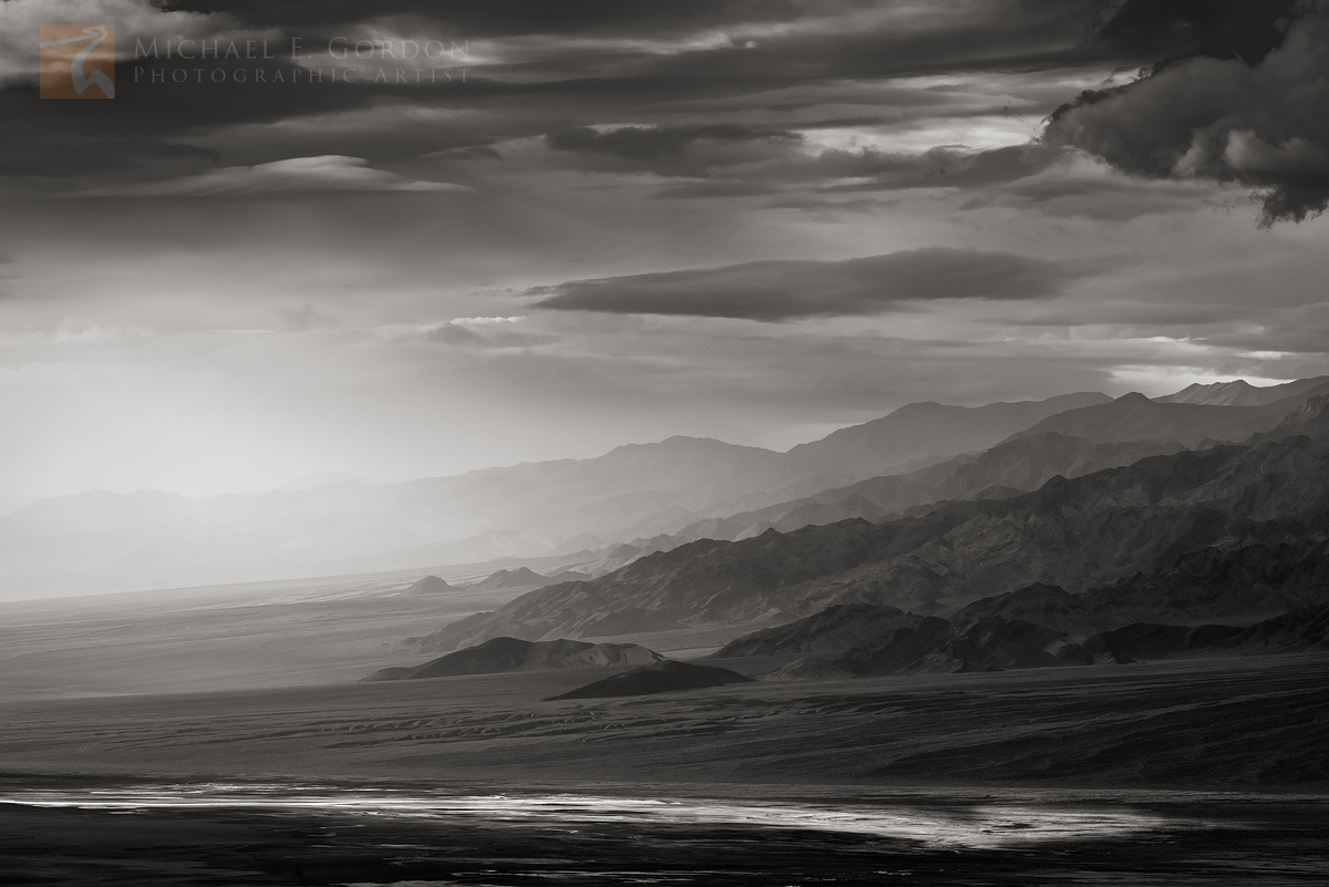 A long view of the Panamint Mountains amidst a stormy sky and momentary window of light. Salt (sodium chloride) and other minerals...