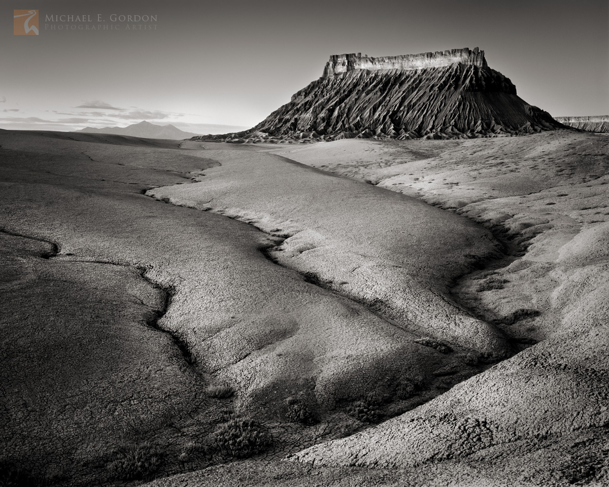 Sunrise unfolds across the smoothly sculpted and&nbsp;eroded Mancos Shale Badlands and Factory Butte. The Henry Mountains are...