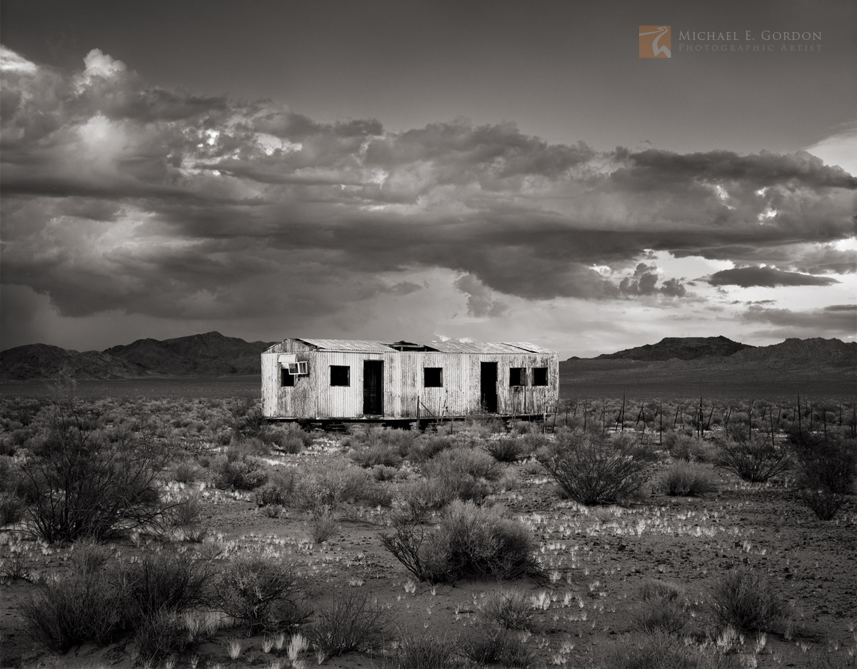 An abandoned shack in California's Mojave Desert framed by thunderstorm cumulus.Logos and watermarks are not found on any printed...