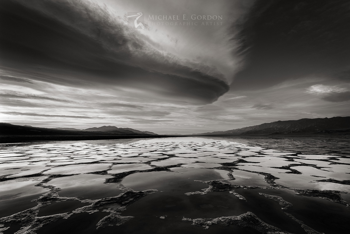 Wild lenticular clouds at sunrise&nbsp;over a flooded Death Valley. The Black and Panamint Mountains are seen in the distance...